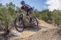 Male cyclist riding his mountain bike down a winding trail through a lush forest