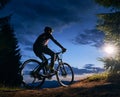 Male cyclist sitting on bicycle under beautiful night sky.