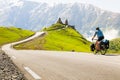 Male cyclist on touring bicycle cycling towards Gergeti trinity church with mountains background. Cycling holidays and travel