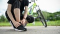 A male cyclist tying his shoelaces before riding a bike on the country roads