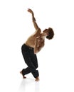 Male dancer, enthusiast in black pants freeze in moment of contemporary dance against white studio background.