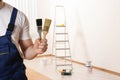 Male decorator with paint brushes in empty room. Space for text Royalty Free Stock Photo