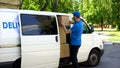 Male delivery worker taking cardboard box from van, parcel shipment service Royalty Free Stock Photo