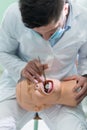 Male dental student practicing on doll.