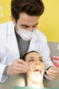 male dentist checking up female patient with mirror