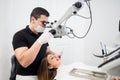 Male dentist with dental tools - microscope, mirror and probe checking up patient teeth at dental clinic office Royalty Free Stock Photo