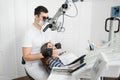 Male dentist with dental tools - microscope, mirror and probe checking up patient teeth at dental clinic office Royalty Free Stock Photo