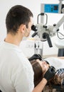 Male dentist with dental tools - microscope, mirror and probe checking up patient teeth at dental clinic office Royalty Free Stock Photo