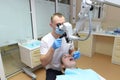 Dentist examines a young beautiful woman, looks at her teeth with a professional microscope in a surgical dental office