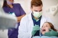 Male dentist examining child`s teeth with dental mirror