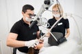 Male dentist and female assistant checking up patient teeth with dental tools. Dental equipment Royalty Free Stock Photo