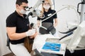 Male dentist and female assistant checking up patient teeth with microscope at dental clinic office. Dental equipment Royalty Free Stock Photo