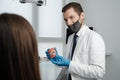 Male dentist holding tooth model with metal braces and speaks to his patient Royalty Free Stock Photo