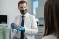 Male dentist holding tooth model with metal braces and speaks to his patient Royalty Free Stock Photo