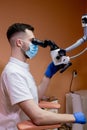 A male dentist looks into a microscope. Modern dentistry using new technologies