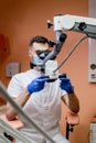 A male dentist looks into a microscope. Modern dentistry using new technologies