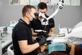 Male dentist performs a dental checkup with the help of microscope