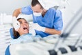 Dentist is treating patient which is sitting in dental chair in clinic Royalty Free Stock Photo