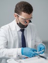 Male dentist wearing dental binocular loupes and checking his medical equipment in dental office