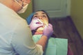 Male dentists examining and working on young female patient.Dentist`s office. Real woman in a chair at the dentist. toned