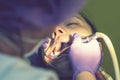 Male dentists examining and working on young female patient.Dentist`s office. Real woman in a chair at the dentist. toned