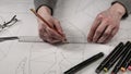 Male designer makes a working drawing. Workplace of a toy designer. Markers, ruler, pen and pencil are on the drawing Royalty Free Stock Photo