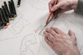 Male designer makes a working drawing. Workplace of a toy designer. Markers, ruler, pen and pencil are on the drawing