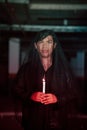 a male devil worshiper with a transparent veil is performing a spooky ritual by holding a candle in his hand Royalty Free Stock Photo