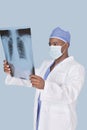 Male doctor analyzing x-ray report over light blue background