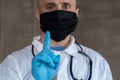 Male doctor in a black mask shows a warning gesture forefinger Royalty Free Stock Photo