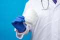 Male doctor in blue latex sterile gloves holds a white disposable mask made of non-woven material Royalty Free Stock Photo