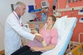 Male doctor caring pregnant woman lying on bed at hospital