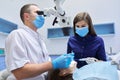 Male doctor dentist treating teeth using dental microscope instruments