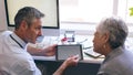 Male doctor discussing over digital tablet with senior woman