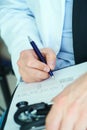 Male doctor on duty in white coat with pen in hand filling prescription or checklist document close up. Selective focus Royalty Free Stock Photo