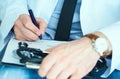 Male doctor on duty in white coat with pen in hand filling prescription or checklist document close up. Selective focus Royalty Free Stock Photo