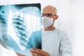 Male doctor in eyeglasses examining the patient chest x-ray film lungs scan at radiology department in hospital.Covid-19 scan body Royalty Free Stock Photo