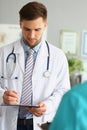 Male doctor filling out patient medical form in clinic Royalty Free Stock Photo