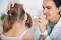 Male doctor examining little girl`s ear at hospital, using flashlight Royalty Free Stock Photo