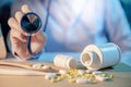 Male doctor hand holding stethoscope over pills on the desk Royalty Free Stock Photo