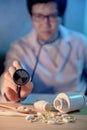 Male doctor hand holding stethoscope over pills on the desk Royalty Free Stock Photo