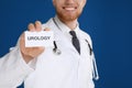 Male doctor holding card with word UROLOGY on background, closeup Royalty Free Stock Photo