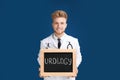 Male doctor holding small blackboard with word UROLOGY on background