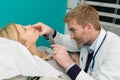 male doctor inspecting young womans neck through magnifying glass