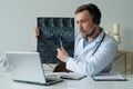 Male doctor listening to patient during telemedicine session. Man doctor having online consultation on laptop holding x Royalty Free Stock Photo