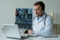 Male doctor listening to patient during telemedicine session. Man doctor having online consultation on laptop holding x Royalty Free Stock Photo