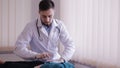 Male doctor makes palpation of the abdomen of the patient. The girl lies on a couch in the doctor`s office.