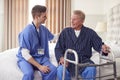 Male Doctor Making Home Visit To Senior Man With Walking Frame For Medical Check In Bedroom Royalty Free Stock Photo