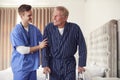 Male Doctor Making Home Visit To Senior Man With Walking Frame For Medical Check In Bedroom Royalty Free Stock Photo