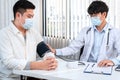 Male doctor in medical face mask is using sphygmomanometer to checking blood pressure to male patient Royalty Free Stock Photo